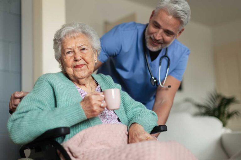 A senior resident using a walker in a well-lit assisted living hallway with grab bars and emergency pull cords visible.