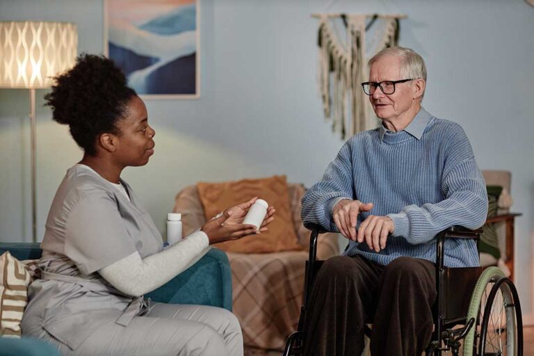 Two older adults using a tablet together while seated at a table, smiling and interacting.